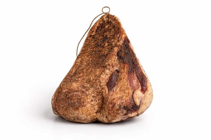 Guanciale di maiale stagionato al pepe intero su sfondo bianco, salume tradizionale italiano per vendita all’ingrosso B2B in Italia ed Europa
