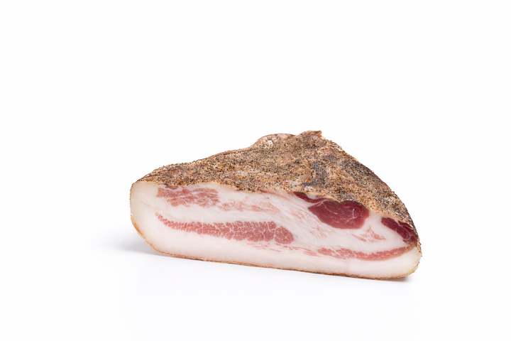 Trancio di guanciale di maiale stagionato al pepe su sfondo bianco, ingrediente tradizionale italiano per vendita all’ingrosso B2B in Italia ed Europa
