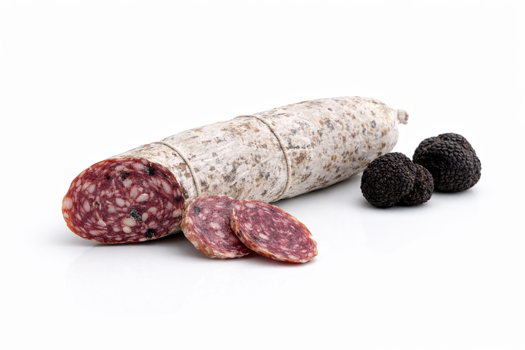 Salame al tartufo artigianale intero disposto in orizzontale su sfondo bianco con due tartufi neri, prodotto gourmet per vendita all’ingrosso B2B in Italia ed Europa
